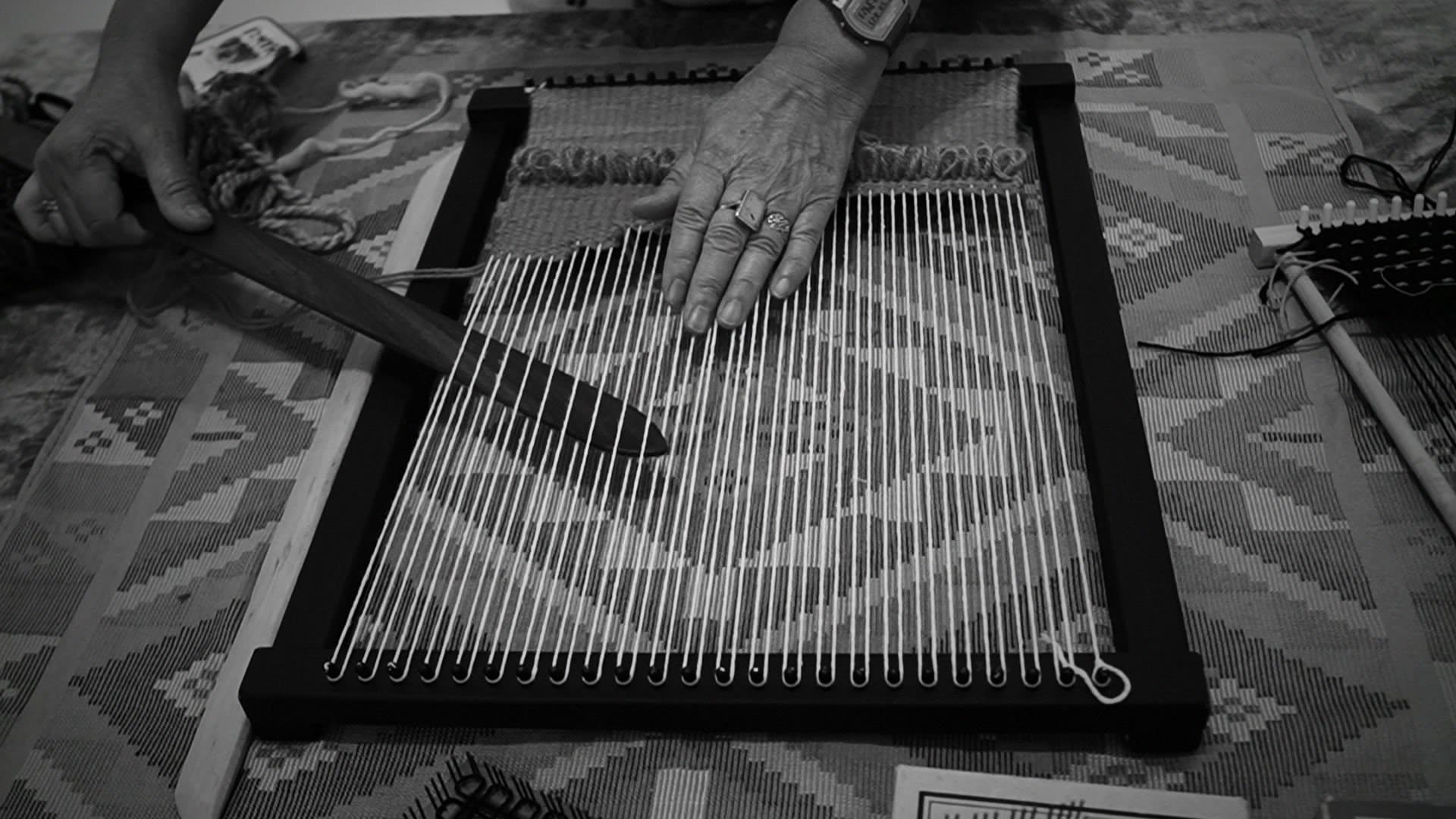 An artisan's hands weaving on a hand loom