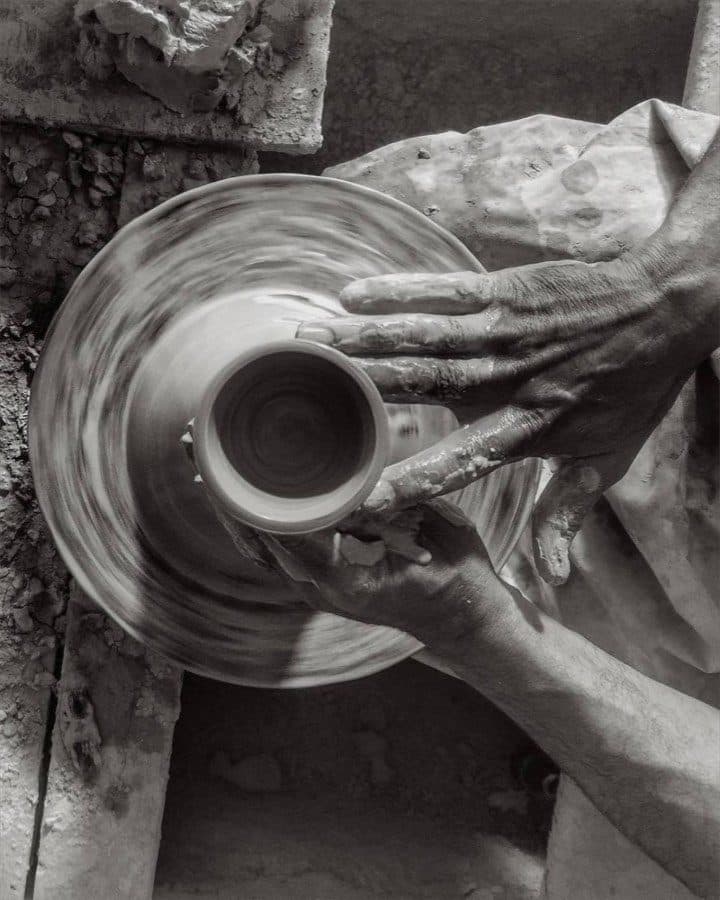 An artisan's hands throwing a pot on the wheel